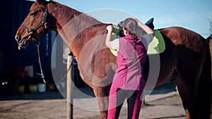 Young beautiful girl dresses a saddle on a horse 60fps 4K