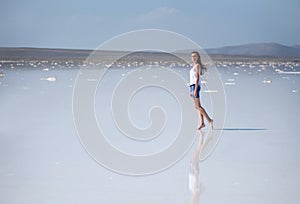 Young beautiful girl on a dry salt lake in the summer at noon