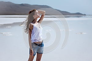 Young beautiful girl on a dry salt lake in the summer at noon