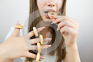 young beautiful girl eating bagels, close-up, crop photo.Attractive brunette sexy woman eating a delicious donut