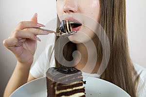 young beautiful girl eating cake, close-up, crop photo. woman\'s mouth eating a piece of cake