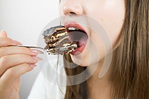 young beautiful girl eating cake, close-up, crop photo. woman\'s mouth eating a piece of cake