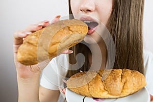 young beautiful girl eating a croissant, close-up, crop photo. female mouth eating croissant