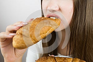 young beautiful girl eating a croissant, close-up, crop photo. female mouth eating croissant
