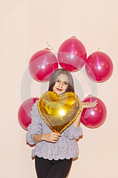 Young beautiful girl embracing heart shaped golden air balloon. valentines day, birthday, womens day, anniversary, holiday