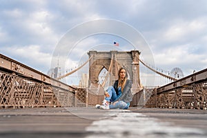 Young beautiful girl enjoying empty Brooklyn Bridge with a magical Manhattan island view