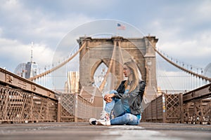 Young beautiful girl enjoying empty Brooklyn Bridge with a magical Manhattan island view