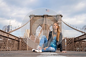 Young beautiful girl enjoying empty Brooklyn Bridge with a magical Manhattan island view