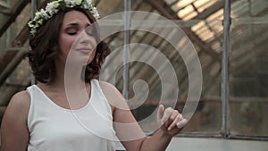 Young beautiful girl with flower circlet and white dress sings and dances outdoors at sunset