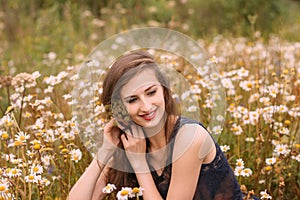 Young beautiful girl with flowers in hair in chamomile field