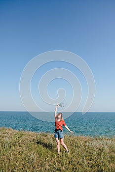 Young Beautiful Girl with Flowers Walking and Dancing on a Beach with smile and joy