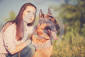 Young beautiful girl with a German shepherd playing on the lawn