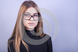 Young beautiful girl with glasses standing in front of grey background