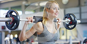 Young beautiful girl in the gym doing exercises on the squat with a barbell, improving the muscles of the buttocks and legs Concep