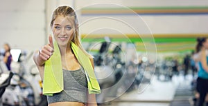 Young beautiful girl in the gym, stands smiling with a towel on her shoulder after the coaching and relaxed. Concept: to love spor