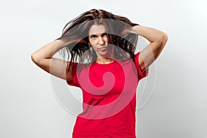 Young, beautiful girl has a disheveled hair, a bad day for hair, isolated on a light background. Different human emotions,