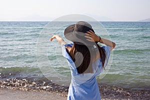 Young beautiful girl in a hat looks at the sea