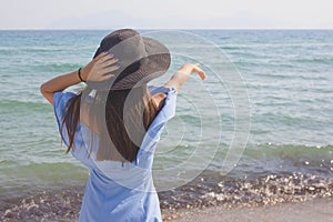 Young beautiful girl in a hat looks at the sea