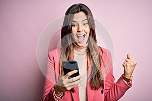 Young beautiful girl having conversation using smartphone over white background screaming proud and celebrating victory and