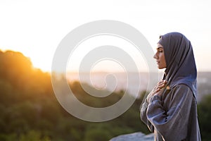 Young beautiful girl in a hijab prays and meditates