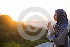 Young beautiful girl in a hijab prays and meditates