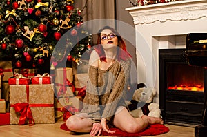 A young beautiful girl holding a glass of champagne and a bottle of her on a New Year`s photo shoot in the studio. The