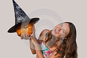 Young beautiful girl holding halloween pumpkin and black witch h