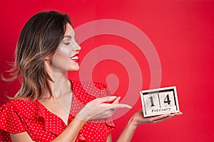 Young beautiful girl holding holding a wooden calendar and smiling on Valentine`s day, copyspace