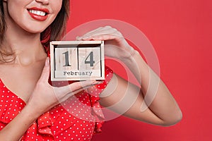 Young beautiful girl holding holding a wooden calendar and smiling on Valentine`s day, copyspace