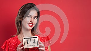 Young beautiful girl holding holding a wooden calendar and smiling on Valentine`s day, copyspace