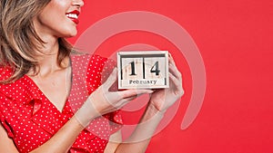 Young beautiful girl holding holding a wooden calendar and smiling on Valentine`s day, copyspace