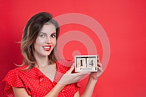 Young beautiful girl holding holding a wooden calendar and smiling on Valentine`s day, copyspace