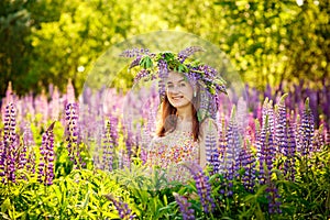 Young beautiful girl holding a large flower with purple lupine in a flowering field. Blooming lupine flowers