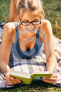 Young, beautiful girl holding an open book, read background summer green park