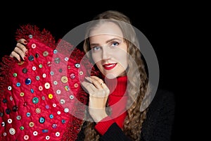 Young beautiful girl is holding red fabric with colorful buttons