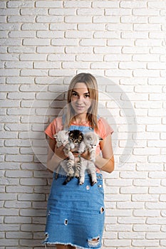 Young beautiful girl holding three little kittens in her arms