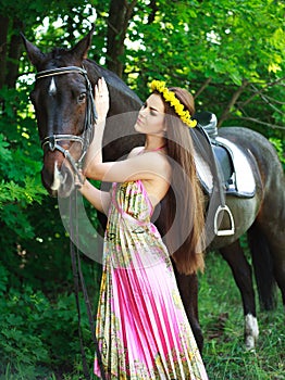 Young beautiful girl with a horse in forest