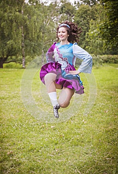 Young beautiful girl in irish dance dress jumping outdoor