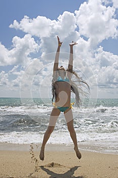 Young beautiful girl jumping at the beach