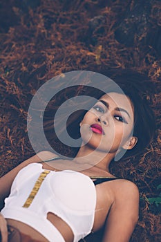 Young beautiful girl laying on the forest floor, with hair tangled in small branches that felled from pine trees, fashion concept