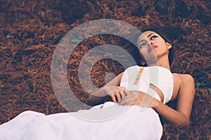 Young beautiful girl laying on the forest floor, with hair tangled in small branches that felled from pine trees, fashion concept