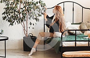 Young beautiful girl with long hair cares for houseplants