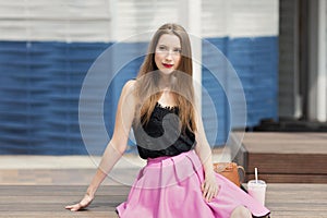 Young beautiful girl with long hair drinks fruit smoothie.