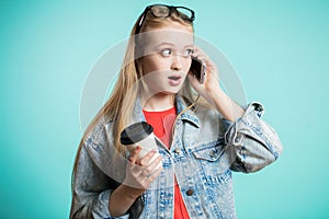 Young beautiful girl with long hair talking on mobile phone on blue background