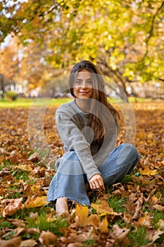Young beautiful girl with long natural hair walks in the autumn park