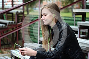 Young beautiful girl look and listening music on your mobile phone the old stadiums bench photo