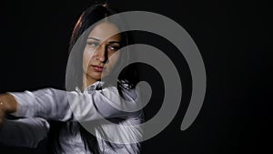 Young beautiful girl looking at camera brutally, holding bat over black background. slow motion