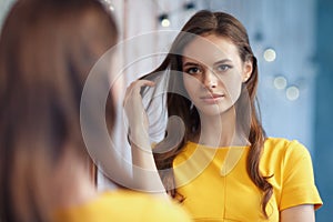 Young beautiful girl looks at herself in the mirror