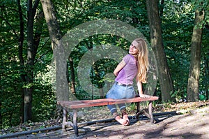 Young beautiful girl model in jeans and a T-shirt with long blond hair and sad smiles pensively posing for a walk in the autumn pa