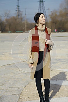 Young beautiful girl model in vest coat of red and beige color and in turtleneck